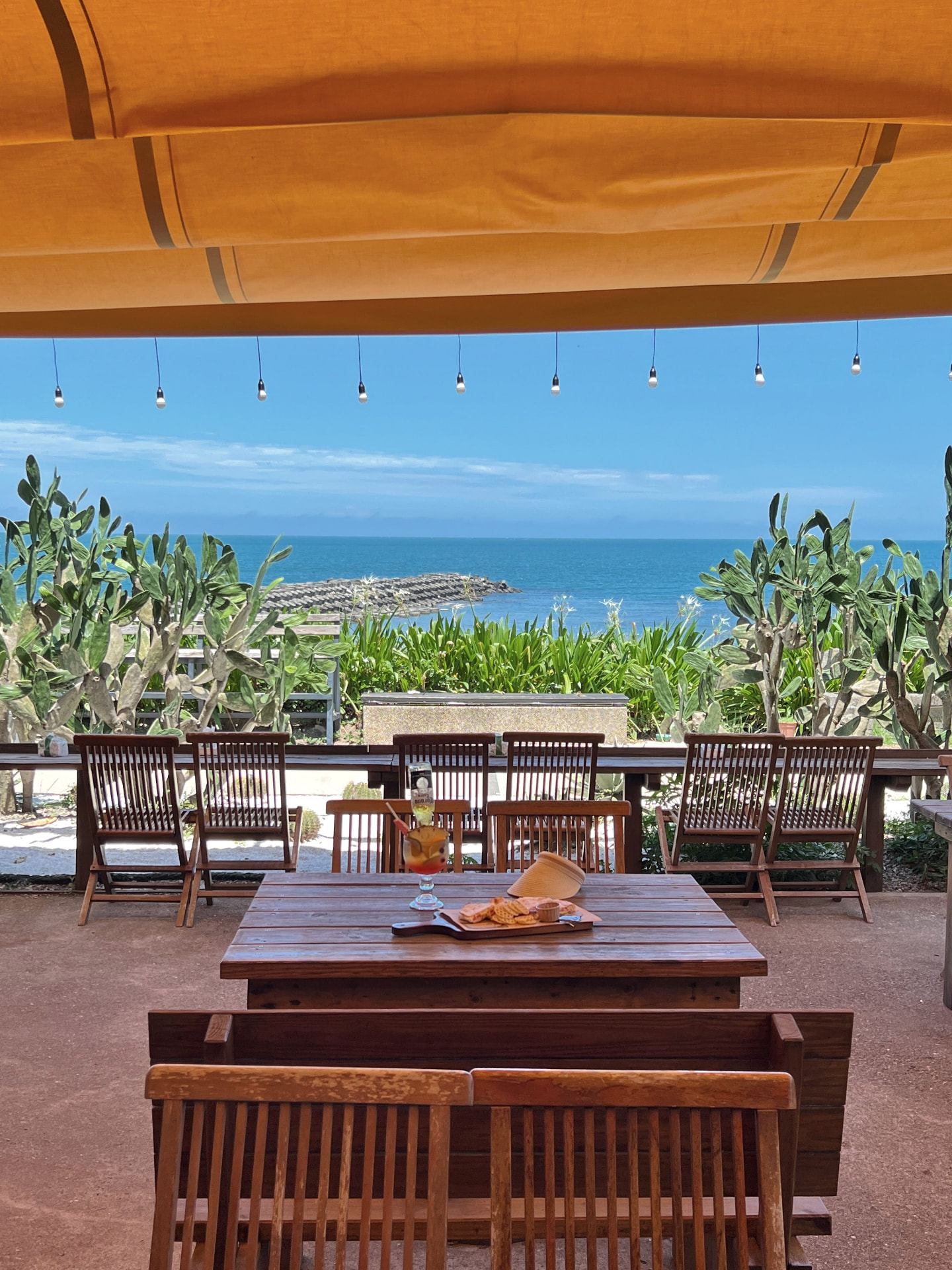 Terrasse sur la mer avec table et chaises en bois sous un auvent orange