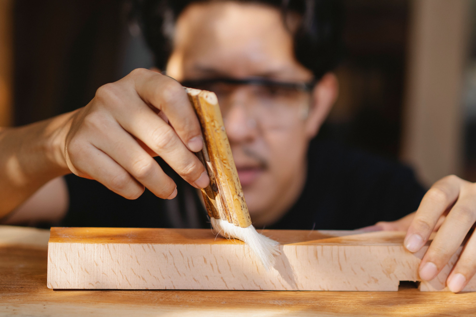 Artisan qui passe un pinceau sur un morceau de bois