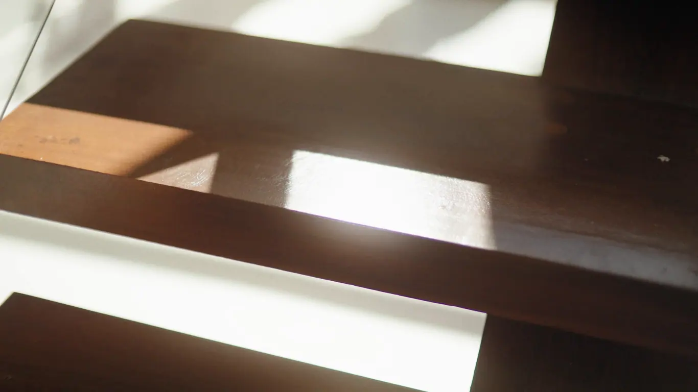 Planches de bois foncé sous la lumière rasante d'une fenêtre